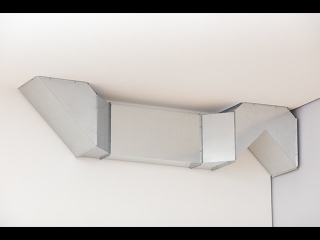 Installation artwork consisting of four combined modular steel units that resemble a rectangular ventilation duct attached to the wall and ceiling. One end is attached to a wall as if emerging from it. It goes sharply up and down and then along the wall until it attaches to the ceiling.